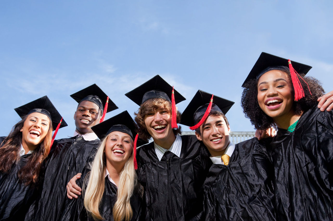A group of high school students smiling in their graduation cap and gowns