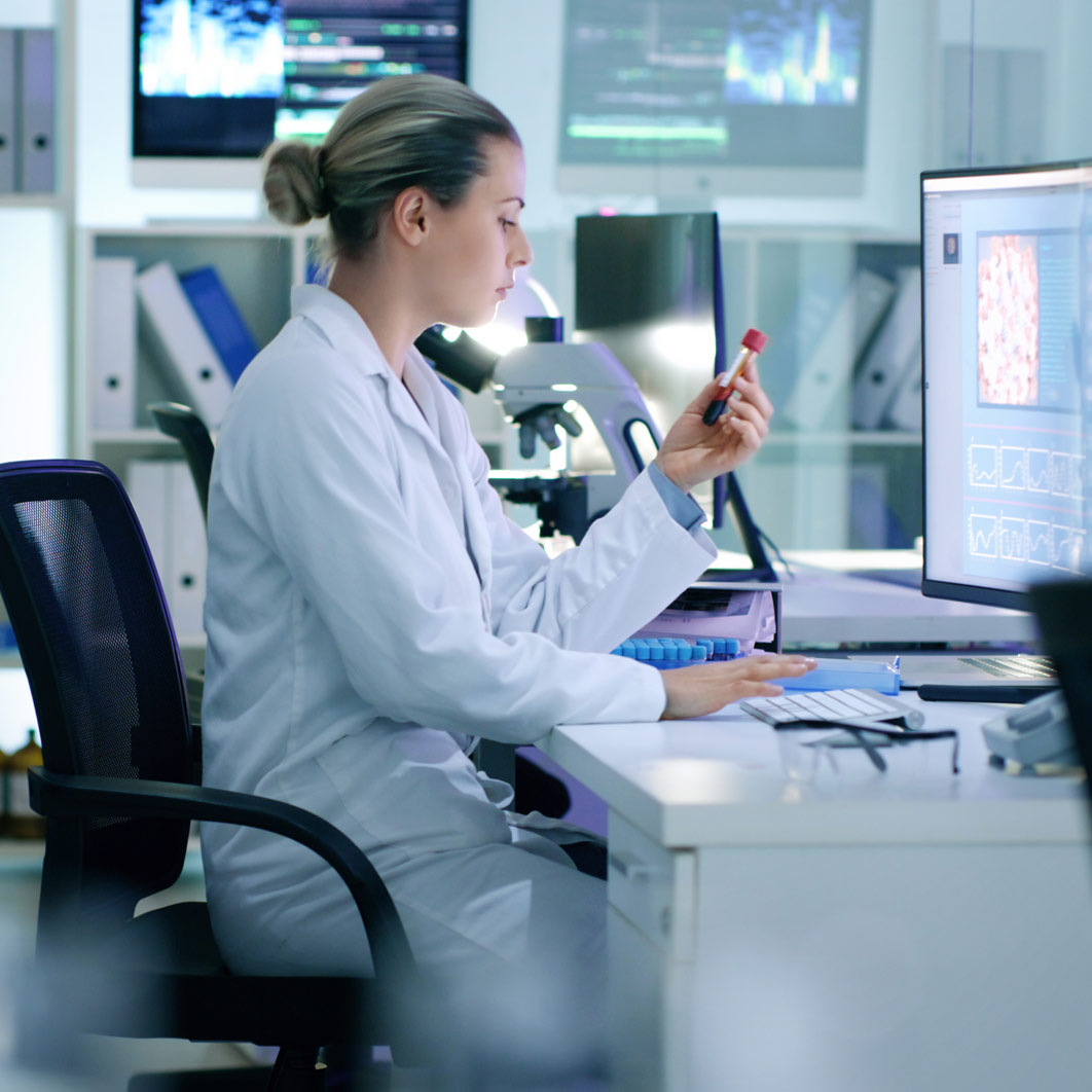 Doctor in a laboratory looking at a vial of blood.