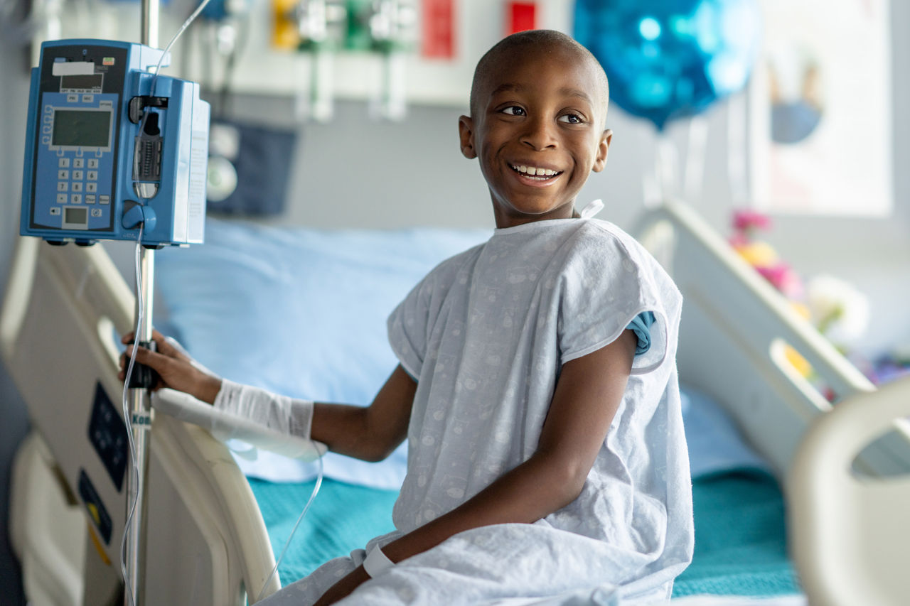 Young boy sitting on a hospital bed smiling at something off camera
