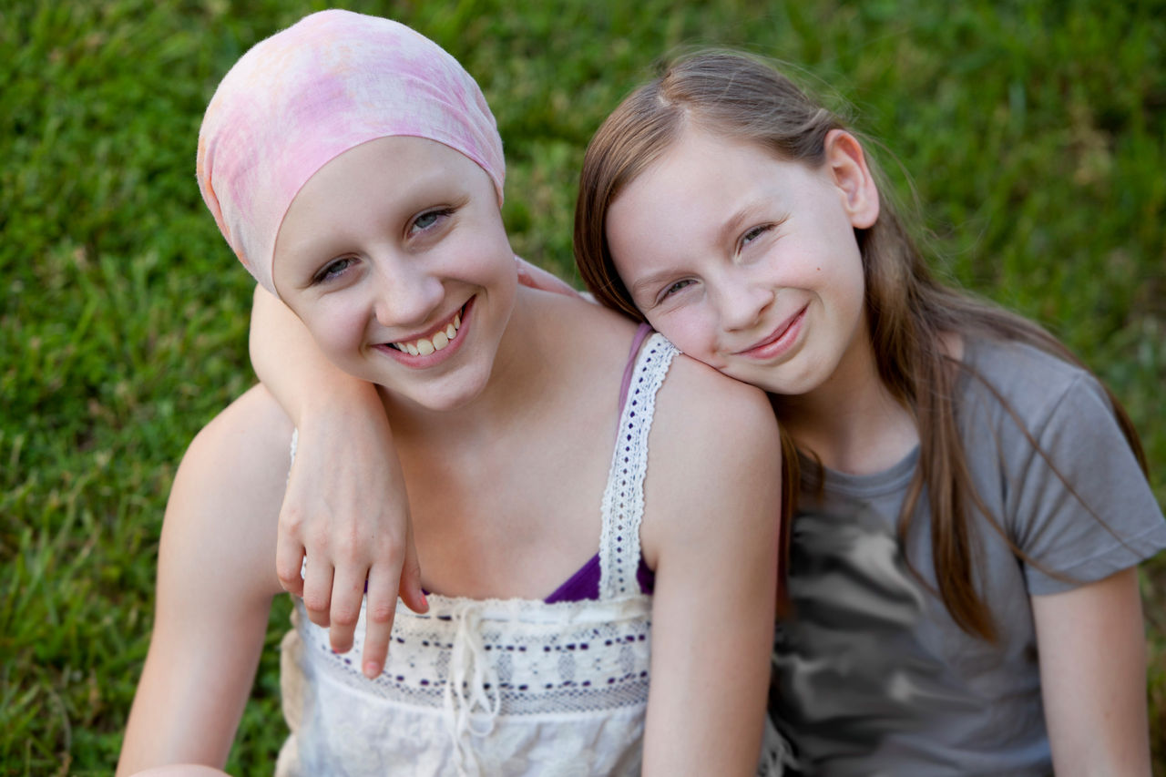 Two teen girls sitting outside hugging