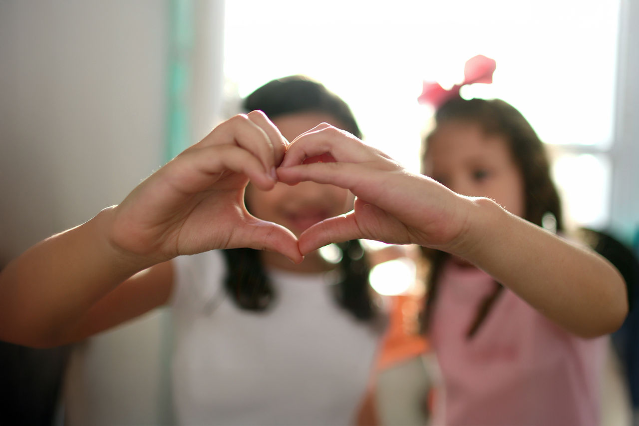 Two children making a heart with their hands.