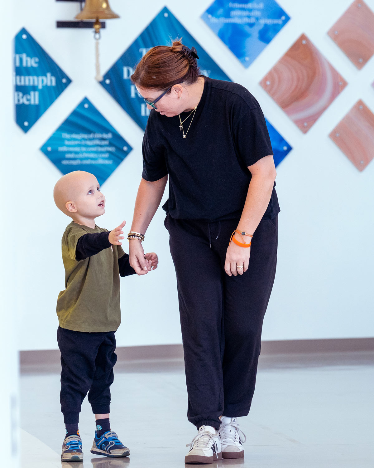 A child holding hands and walking with a nurse away from the cancer bell