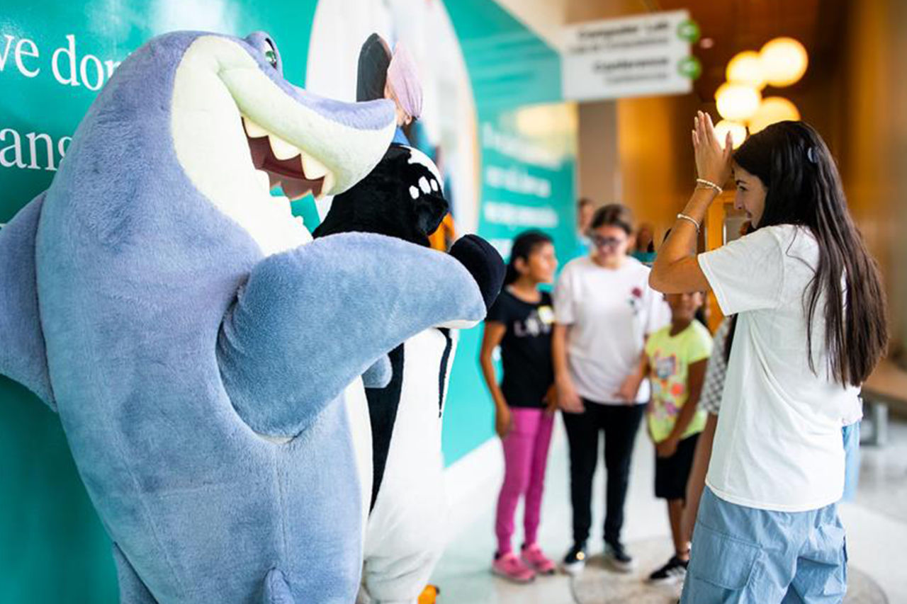Child with shark mascot at cochlear implant-summer camp