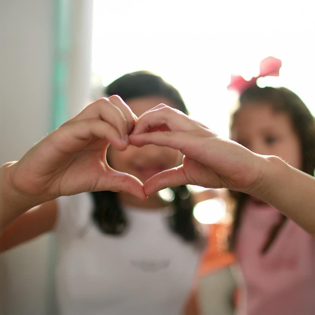 Two children making a heart with their hands.